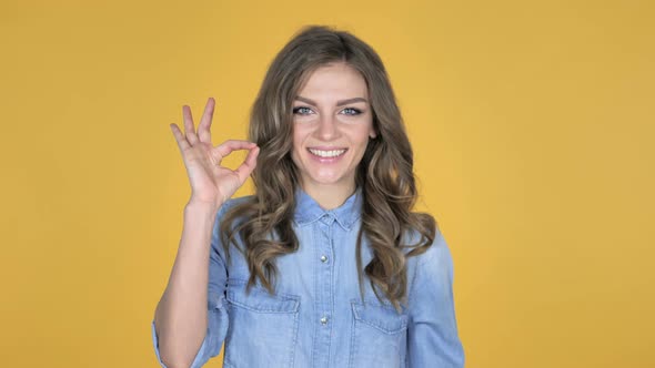 Okay Sign By Young Girl Isolated on Yellow Background