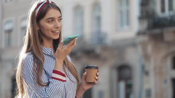 Beautiful Young Woman Using a Smartphone Voice Recognition Function Online Standing on the Old City