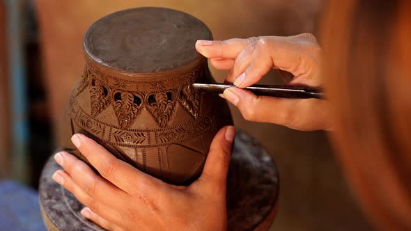 Hands make potter inflicts a decorative pattern on earthenware