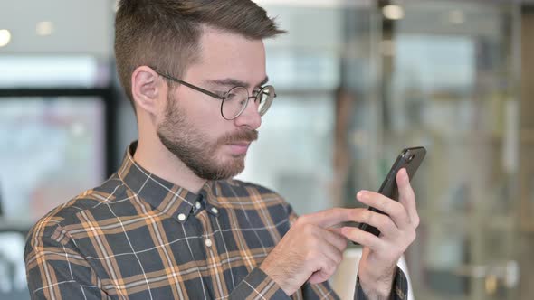 Portrait of Focused Young Designer Using Smartphone