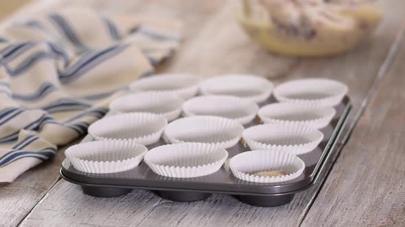 Pouring Blueberry Batter Into Muffin Cups. Woman Baking Blueberry Muffins