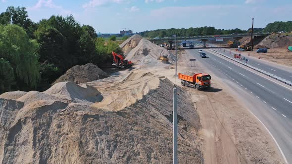 Pile of rubbles near the road. Truck full of stones moving out into the highway.