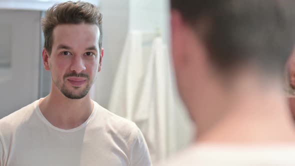 Young Man Smiling at Camera In Mirror