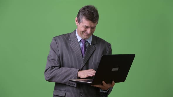 Mature Handsome Businessman Against Green Background