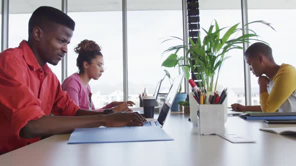 African american creative businessman celebrating in office, with diverse female colleagues working