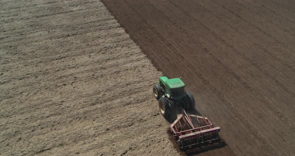 Farm Tractor Plows the Field and Prepares for Sowing