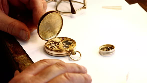 Hands of horologist repairing a pocket watch