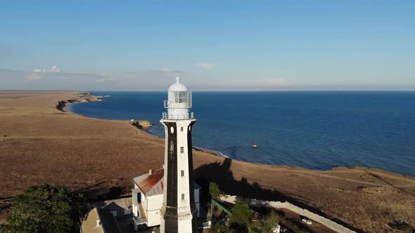 Aerial View of an Unknown Lighthouse with Black and White Edges on the Peninsula's Promontory