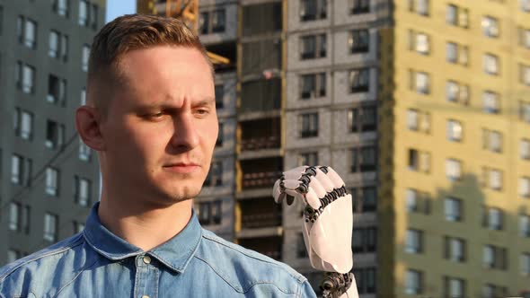 Young Man Looks on His Robotic Hand