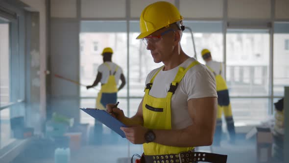 Senior Foreman Checking and Inspecting with Clipboard at Construction Site