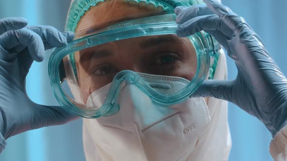 Female Doctor Or Nurse Puts On a Medical Mask, Goggles, a Disposable Cap, Hazmat