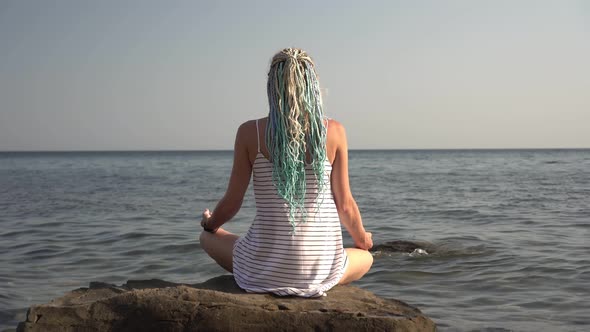 A Woman Meditates in the Lotus Position on the Seashore