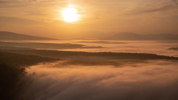 Stunning Orange Sunrise with Sea Clouds Drifing in a Valley Among Mountains