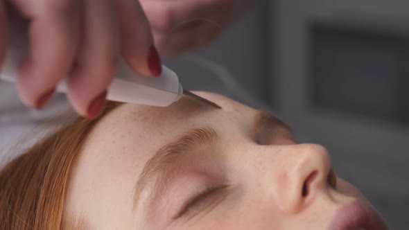 Young Woman Receives an Ultrasound Facial Cleaning in a Beauty Salon From a Cosmetologist. Concept