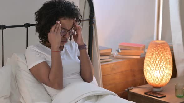 African Woman with Headache Sitting in Bed