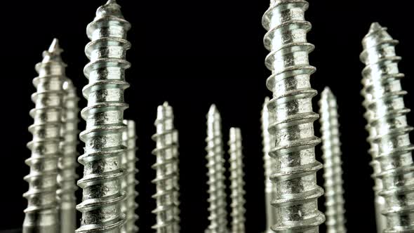 Metal Screws Stainless Bolts Steel Anchors with Screw Threads Rotating on Black Background