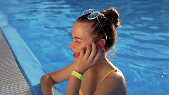 A Young Woman is Talking on the Phone in the Water She is Calling a Friend