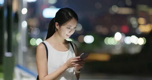 Woman use of mobile phone in city at night