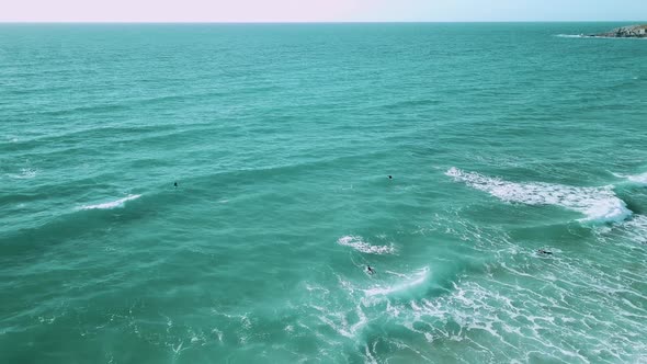 Wide shot of surfers swimming against the tide. Wide drone-shot.