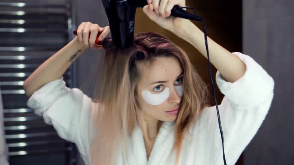 Woman in Bathroom Mirror and Drying Her Hair with Hair Dryer and Brush