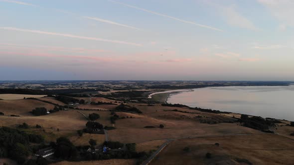 Aerial view of the coastline of Sejerøbugten with hills, fields and ocean.