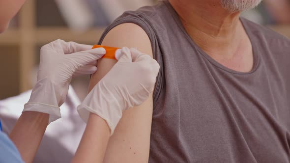 Asian old man got vaccine injection with a syringe needle for an elderly Senior patient. Doctor wear