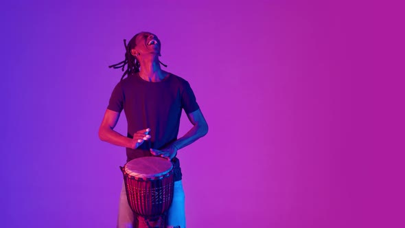 Black Man Laughs Playing an African Drum and Dancing in the Studio