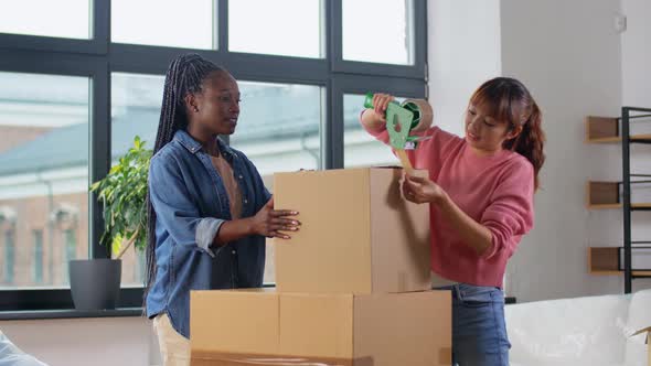 Women with Adhesive Tape Packing Boxes at Home