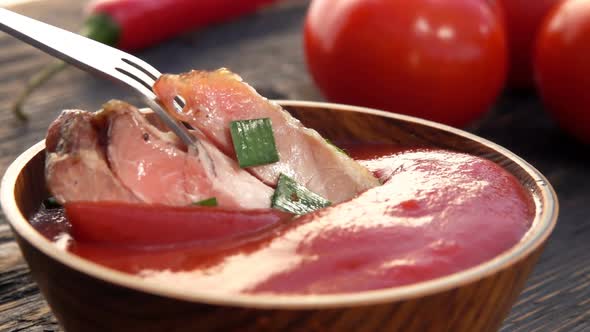 Closeup of the Juicy Grilled Ribs on the Fork Dipped Into Ketchup in a Bowl