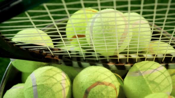 Tennis balls and racket in bucket at studio 4k