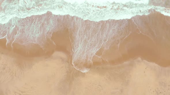 Static top shot aerial drone showing endless wild sea waves breaking on the sandy coast in slow moti