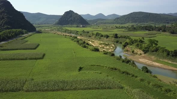 Aerial Motion River and Fields on Banks Against Mountains