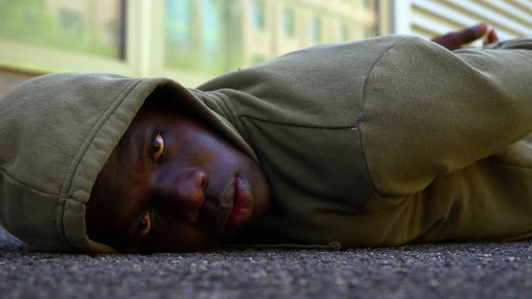 hooded black man lying on the ground stares at camera - protest symbol