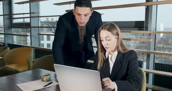 Portrait of a Man and a Woman Discussing Work with Notebook in the Brightly Lit Modern Office