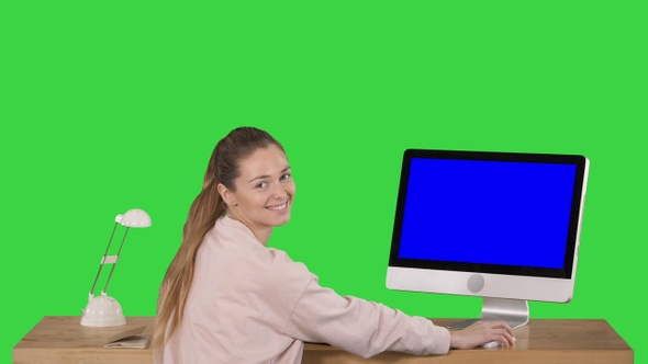 Cheerful woman sitting at the table with a computer in