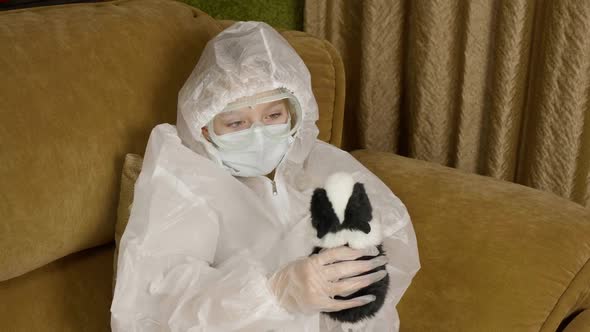 Sick Teenager Girl in Protective Costume Playing with Hamster on Home Sofa While Quarantine