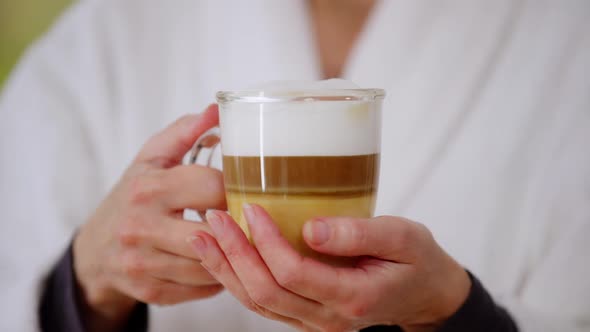 Closeup Transparent Coffee Cup with Cappuccino in Mature Female Hands