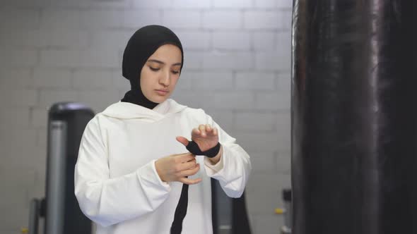 Arab Woman in Muslim Sportswear Ties Elastic Bandages on Her Arms