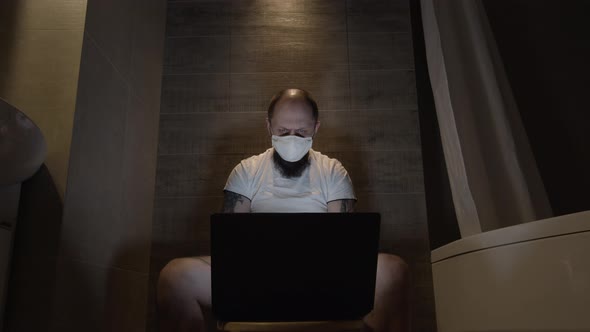 A Man on Self-isolation Works in the Toilet on a Laptop