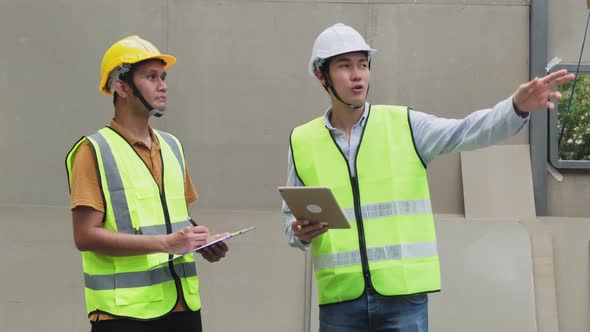 Asian colleague male workers people wearing protective safety helmet and work at construction site.