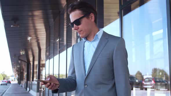 Elegant businessman using smartphone in airport. Young mail entrepreneur.