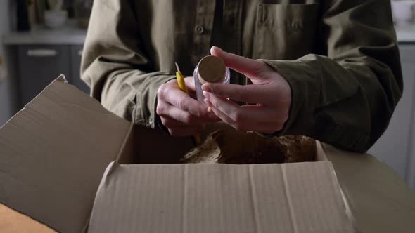 woman unpacking a box of cosmetics in the kitchen at home