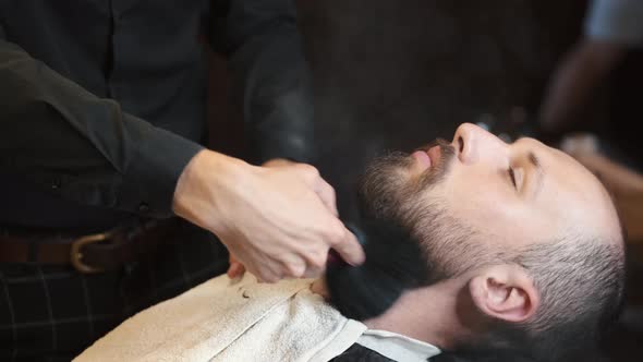 Barber Applying Lotion on Mans Beard 