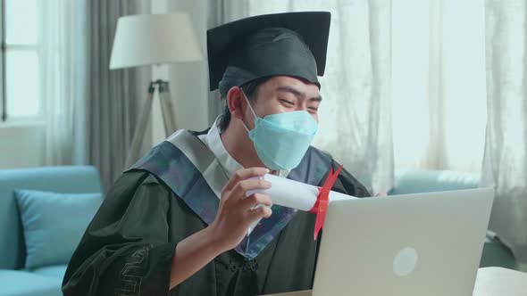 Man Wearing Protection Face Mask Showing A University Certificate During An Online Video Call