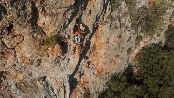 Aerial Drone POV of Strong Muscular Man Climbing Challenging Route on Vertical Crag with Tufa