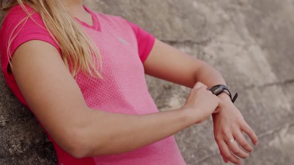 Woman looking at her watch against a wall