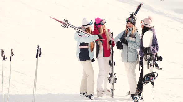 Women Snowboarders and Skiers on Mountain Slope Talking and Relaxing After Slide