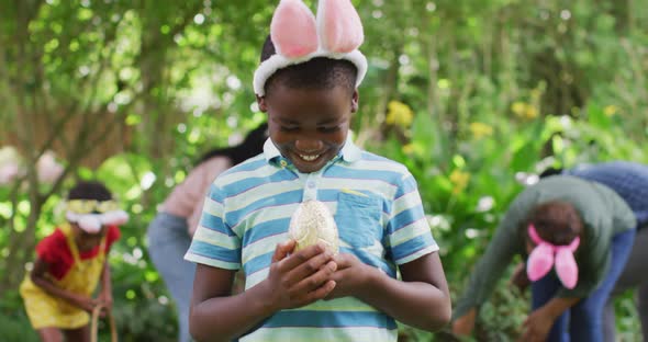 Animation of happy african american boy holding easter egg in garden