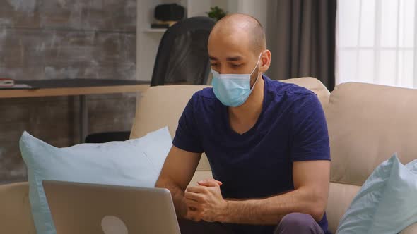 Man Wearing Mask Waving at Laptop Screen