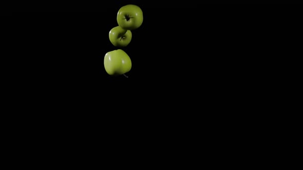 Close Up at the Group of Three Apples Fly Up and Spinning on a Black Background in Slow Motion Shot